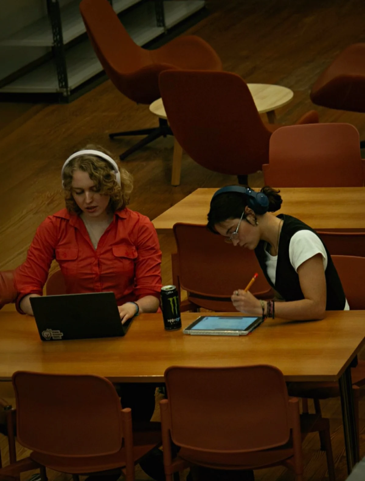 Vic y Ju trabajan con una laptop y una tablet en la biblioteca.